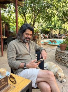 Huésped consultando opiniones en el móvil junto a su perro en la terraza con piscina de Mas Torrencito